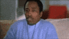 Movie gif. Wearing a light blue shirt and a necklace, Eddie Griffin watches something offscreen with interest while eating popcorn.