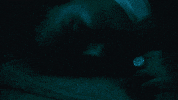 Music video gif. From the video for Thought About That, Noa Kirel appears to be asleep for a moment before her face is lit up and her eyes open.