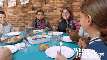 Movie gif. Kids pound silverware on a round table as we pan to see Michael Moore in Where to Invade Next pounding his silverware at the table with them.