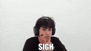 Video gif. Man sits with big headphones on his head. He rubs his chin and then sighs. Text, “Sigh.”