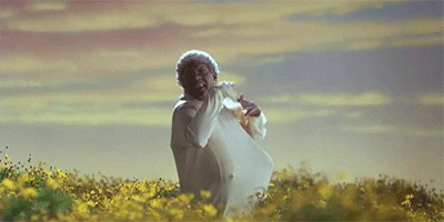 Movie gif. Eddie Murphy dressed as Grandma Klump in The Nutty Professor 2 jumps around happily in a field of flowers wearing a white dress.
