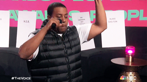 TV gif. Kenan Thompson from "The Voice" wearing a black puffer jacket pumps his fist and looks hyped, saying "boom."