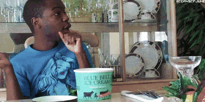 Video gif. Man holds a spoon while sitting at a table with a tub of Blue Bell Ice Cream sitting on top. He sassily points to someone offscreen with his finger and spoon and says with raised eyebrows, "Cute for you," which appears as text.