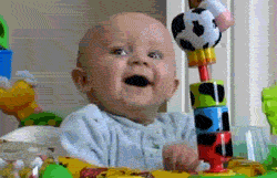 Video gif. A baby in a play seat goes from happy and smiling to suddenly startled in a wide-eyed expression. 