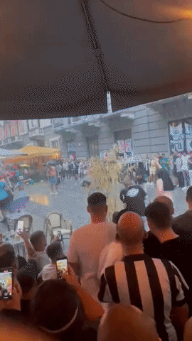 Newcastle Fan Slides Along Street as Heavy Rain Soaks Supporters in Milan