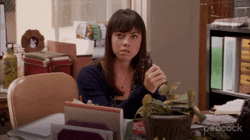 TV gif. Aubrey Plaza as April from Parks and Rec sits at a desk and slowly holds up a pair of scissors by the blade, a menacing look in her eye. 