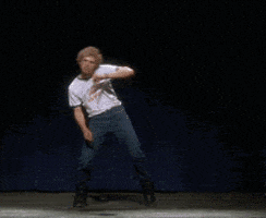 Movie gif. Jon Heder as Napoleon in Napoleon Dynamite dances a choreographed dance on stage, putting his whole body and energy into it, reaching his arms in every direction, while wearing his snow boots. 