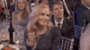 Celebrity gif. Nicole Kidman sits at a table at the 2020 SAG Awards smiles and shrugs her shoulders.