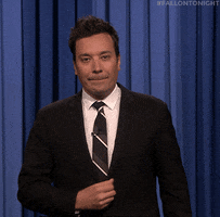 Tonight Show gif. Jimmy Fallon briefly waves goodbye to the audience before quickly dipping out of frame on his way off of the stage.