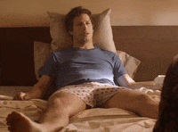 Movie gif. Andy Samberg as Nyles in Palm Springs lays in bed appearing depressed, propped up on a pillow, and says "Kill me," which appears as text.