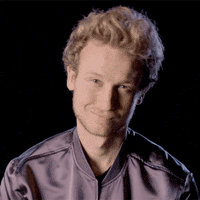 Video gif. A man smiles with closed lips and gives us a wink.