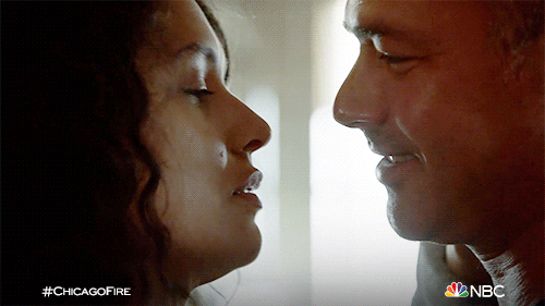 TV gif. Miranda Rae Mayo as Stella and Taylor Kinney as Kelly on Chicago Fire lean in for a kiss.