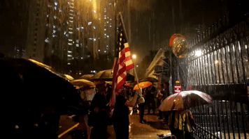 Protester Waves American Flag, Sings 'The Star-Spangled Banner' at Rainy Police Station Demonstration