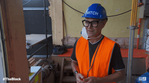 TV gif. The Block contestant Mitch, wearing a hard hat, lifts up both hands, crosses his fingers, and says, “fingers crossed!”