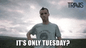 Celebrity gif. Slow zoom in on Fran Healy wearing a gray t-shirt, standing alone on an empty plain. He gives us a cold, unhappy stare. Text, "It's only Tuesday?"