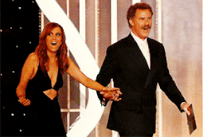 Celebrity gif. Kristen Wiig and Will Ferrell walk out hand in hand to present at the Golden Globes and stare at their surroundings in exaggerated awe.