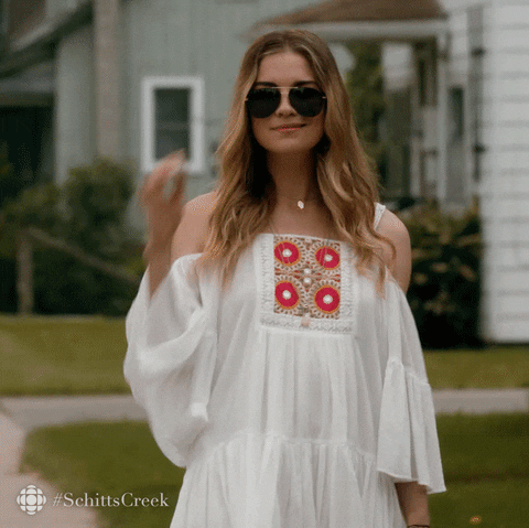 Schitt's Creek gif. Annie Murphy as Alexis saunters towards us as she slowly lowers her aviators, peering over them with a sly smile.