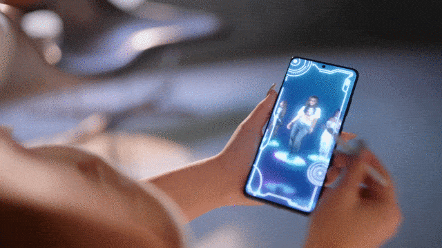 Celebrity gif. Noa Kirel swipes through a futuristic phone, with multiple videos of her dancing in different outfits.