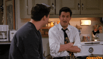 Friends gif. Matthew Perry as Chandler and Matt LeBlanc as Joey sitting in their apartment as they burst into laughter together.