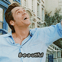 Movie gif. In front of a row of townhouses on a sunny day, Jim Carrey as Bruce in Bruce Almighty spreads his arms and smiles at the sky to say: Text, "B-e-a-utiful."