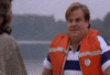 Movie gif. Chris Farley as Tommy in Tommy Boy wears an orange life vest and sits across from a woman. He shakes his head out of disbelief and chuckles as he says, “That was awesome!”