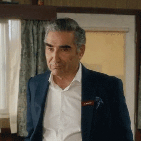 Schitt's Creek gif. Eugene Levy as Johnny leans forward and opens his mouth wide before smiling as he bounces with his hands in his pockets. Text, "Ha."