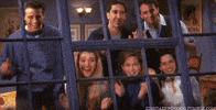 Friends gif. Matt Leblanc, Lisa Kudrow, David Schwimmer, Jennifer Aniston, Matthew Perry, and Courteney Cox as their characters on Friends happily applaud someone through large steel blue windows that looks into their cozy space.