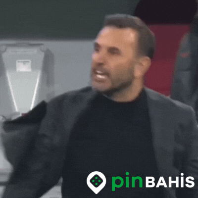 Sports gif. Okan Buruk, a soccer manager, stands angrily on the sidelines as he shouts and aggressively points out at the field repeatedly. 