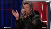 Reality TV gif. Blake Shelton on The Voice grins as he claps his hands energetically. 