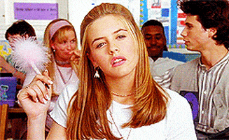 Movie gif. Alicia Silverstone as Cher in Clueless holds a fluffy pen while sitting in a classroom staring pensively into general space as if lost in deep thought.