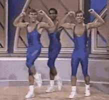 Video gif. Grainy footage shows three men in blue singlets dancing in unison. They snap their fingers, spin and pump their arms before looking up with sunglasses on. Text, "Deal with it." 