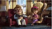 Disney gif. Carl and Ellie Fredrickson from Up are adults and sit in their living room. They both read books in separate chairs while they hold hands. 