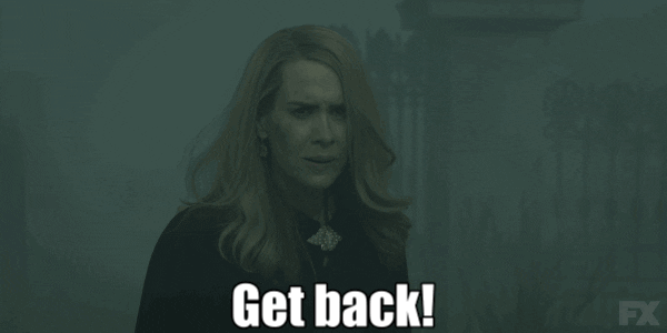 TV gif. Sarah Paulson as Cordelia on American Horror Story breathes deep and reaches her hand forward, shouting, "get back!" which appears as text.
