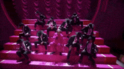 Oscars 2024 GIF. Ryan Gosling is performing I'm Just Ken and he sits on steps with his male posse, all of them holding a champagne glass. They raise their glasses in unison, whip it down to break it, and end with stabbing themselves with the faux broken glass. 