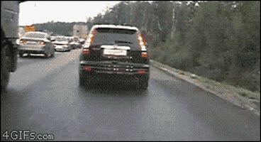 Video gif. Small silver car speeds past a black SUV on the shoulder and rams right into the road bumper. The black SUV pauses for a moment before simply moving on.