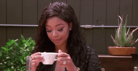 Reality TV gif. DJ Duffey from Basketball Wives smiles and sips tea.