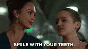 TV gif. Jessica Alba as Detective Nancy from L.A.'s Finest tells Sophia Reynolds as Isabel McKenna to "Smile with your teeth," and provides a huge, teethy smile to demonstrate.