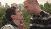 Music video gif. Steve Grand in the video for Stay kisses a man in various idyllic scenes around a city, in a park, and near a waterfront.