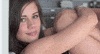 Video gif. Girl leans on a wall, hugging her knees up close to her head. She looks at us flirtatiously, giggly and smiling.