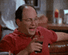 Seinfeld gif. Jason Alexander as George winks and points his finger across the table.