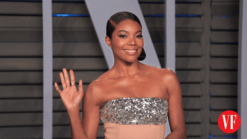 Celebrity gif. Gabrielle Union is posing for Vanity Fair and waves from the red carpet.