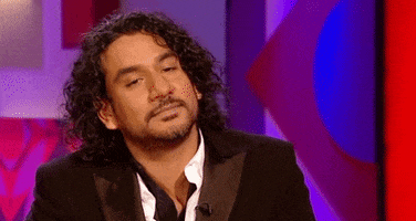 Celebrity gif. Naveen Andrews is leaning back and considers a question before opening his mouth to speak.
