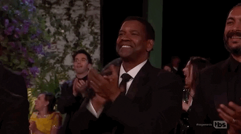 Celebrity gif. Denzel Washington is standing up during an award and is clapping heartily, looking immensely proud.