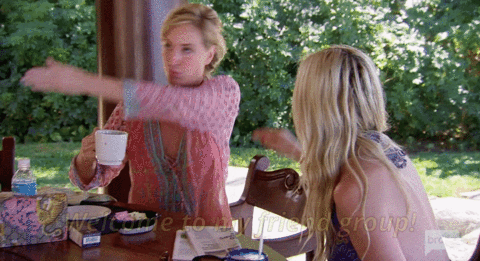Reality TV gif. Sonja Morgan is eating at an outdoors patio and she holds a mug in one hand while waving with the other broadly, sweeping over the area and exclaiming, "Welcome to my friend group."