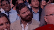 Academy of Country Music Awards gif. Jordan Davis while seated looks attentively in one direction before chuckling and looking in the other direction as if he is feeling shy.