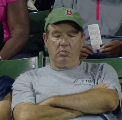 Video gif. Middle aged white man in a baseball cap sits in bleachers with arms folded across his chest. His eyes are closed and his head drops like he's nodding off to sleep.