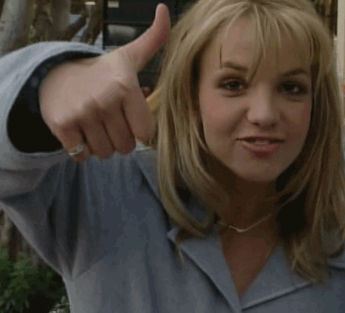 Celebrity gif. Young Britney Spears is throwing us a big thumbs up, pursing her lips and grinning.