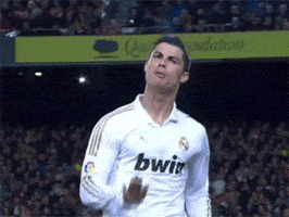 Sports gif. Cristiano Ronaldo of Real Madrid, on the field in his bwin jersey, gesturing to us with a flat hand pressing downward to stay calm or keep it down, then pointing to himself and repeating the gesture.