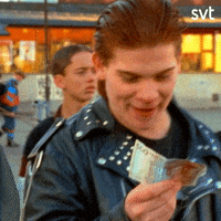 Video gif. Young man wearing a black leather jacket with slicked-back hair clutches a $500 Swedish bill, smiling in excitement.