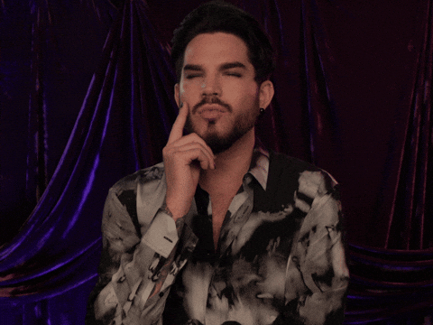 Celebrity gif. Adam Lambert ponders something while he taps his chin.